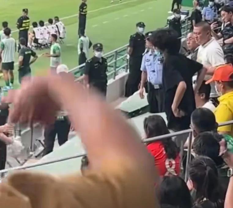 面对一个穿着上港队红色球衣的女子，一大群北京球迷群起而攻之，女球迷在安保人员的护(3)