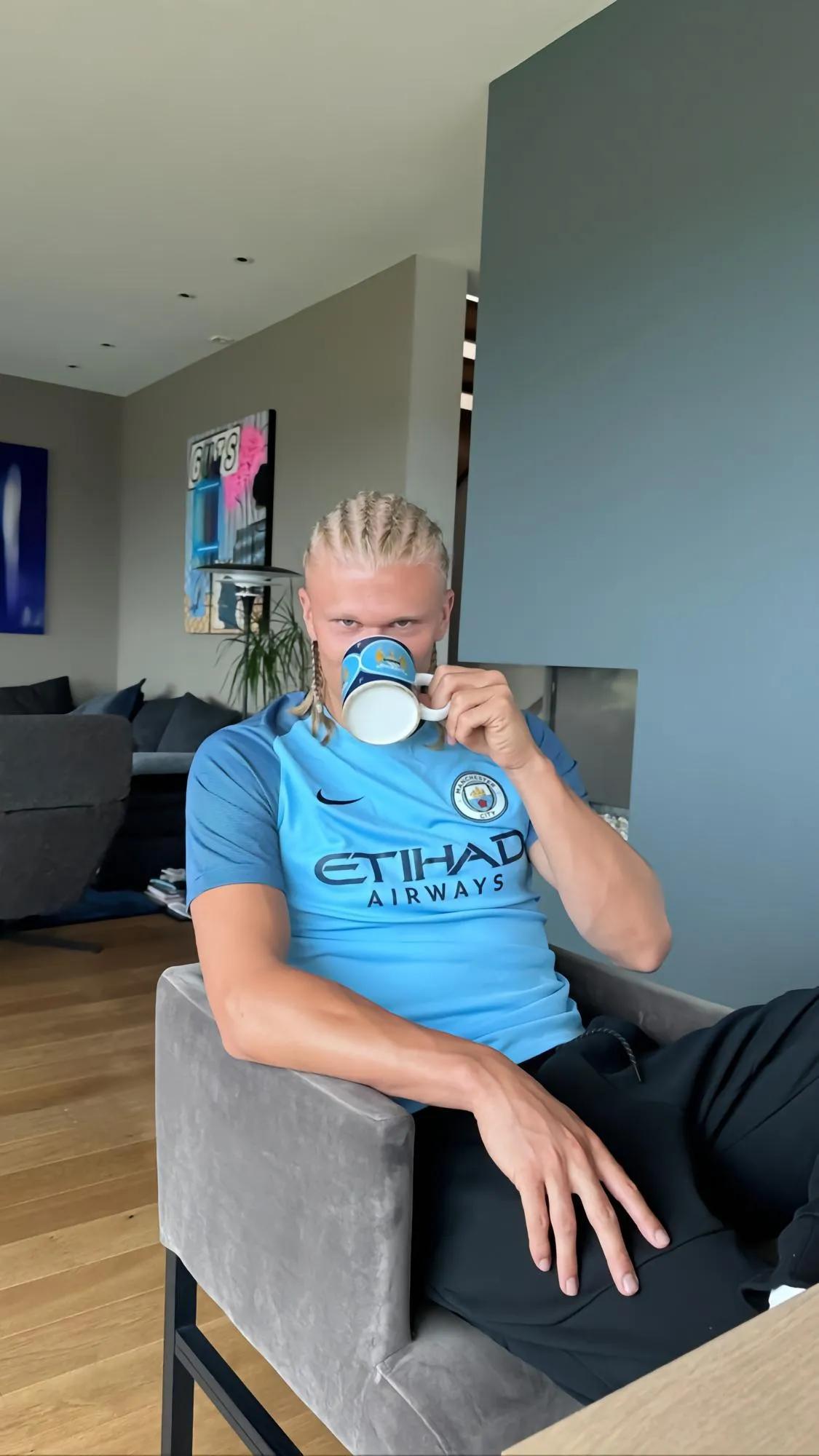 哈兰德身穿曼城球衣，用曼城马克杯喝水的照片。
球衣是曼城老球衣，被子上是曼城的老(1)